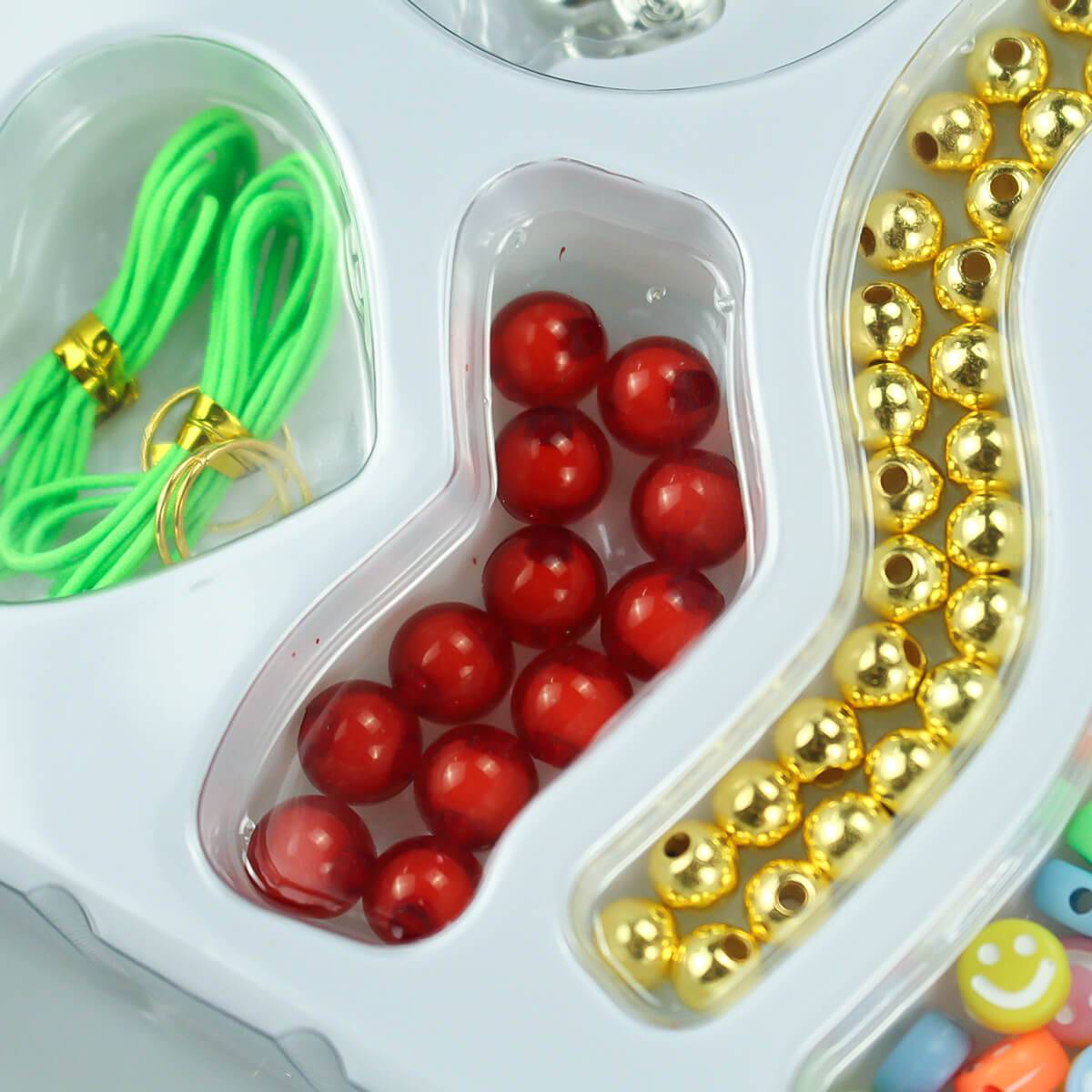 Kids' DIY jewelry-making kit with red and gold beads, green string, and accessories. Perfect for creative crafting and personalized designs.