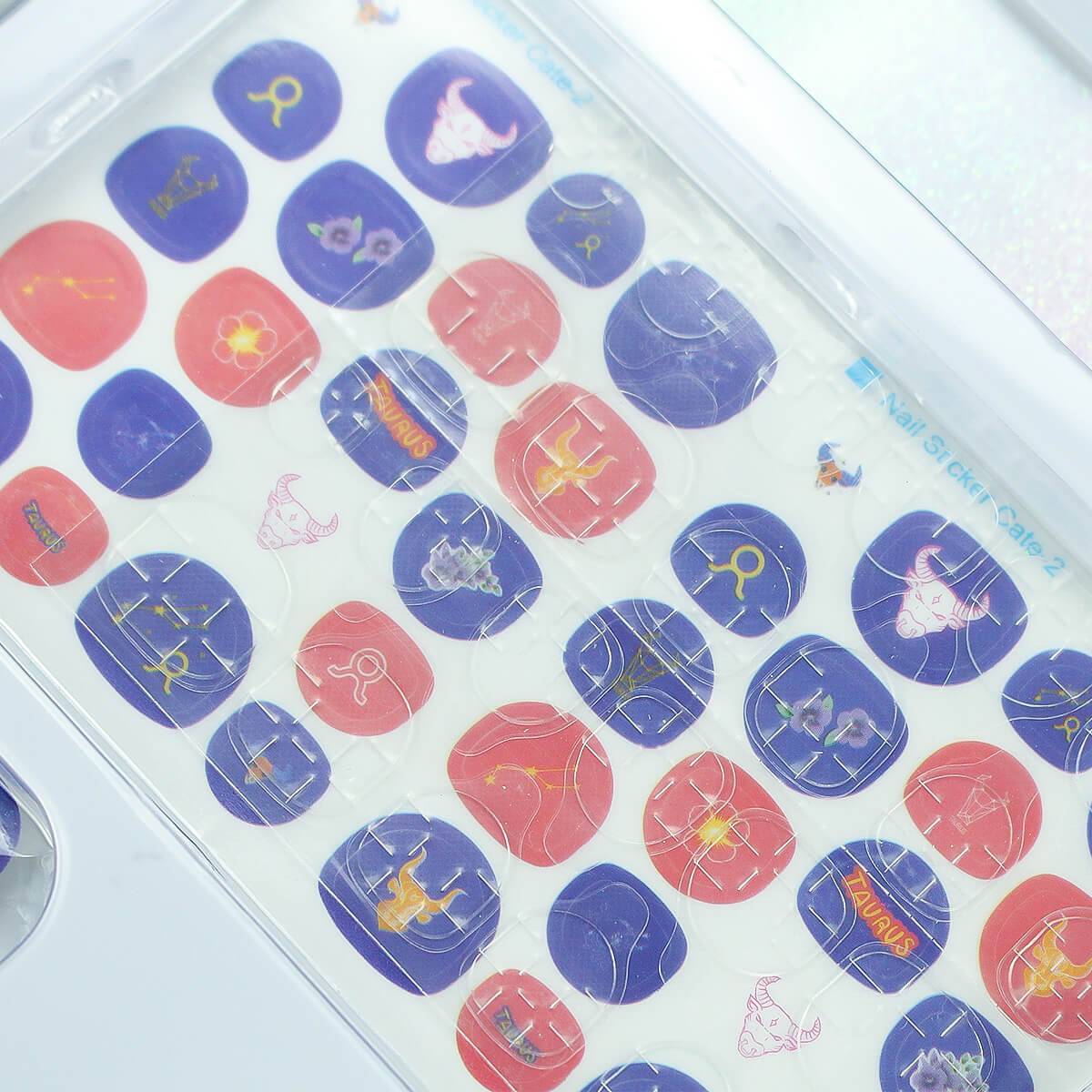 Close-up of Taurus-themed nail stickers from the 12 Zodiac Signs Kids Nail Art Set HW23158395, featuring purple and red designs.