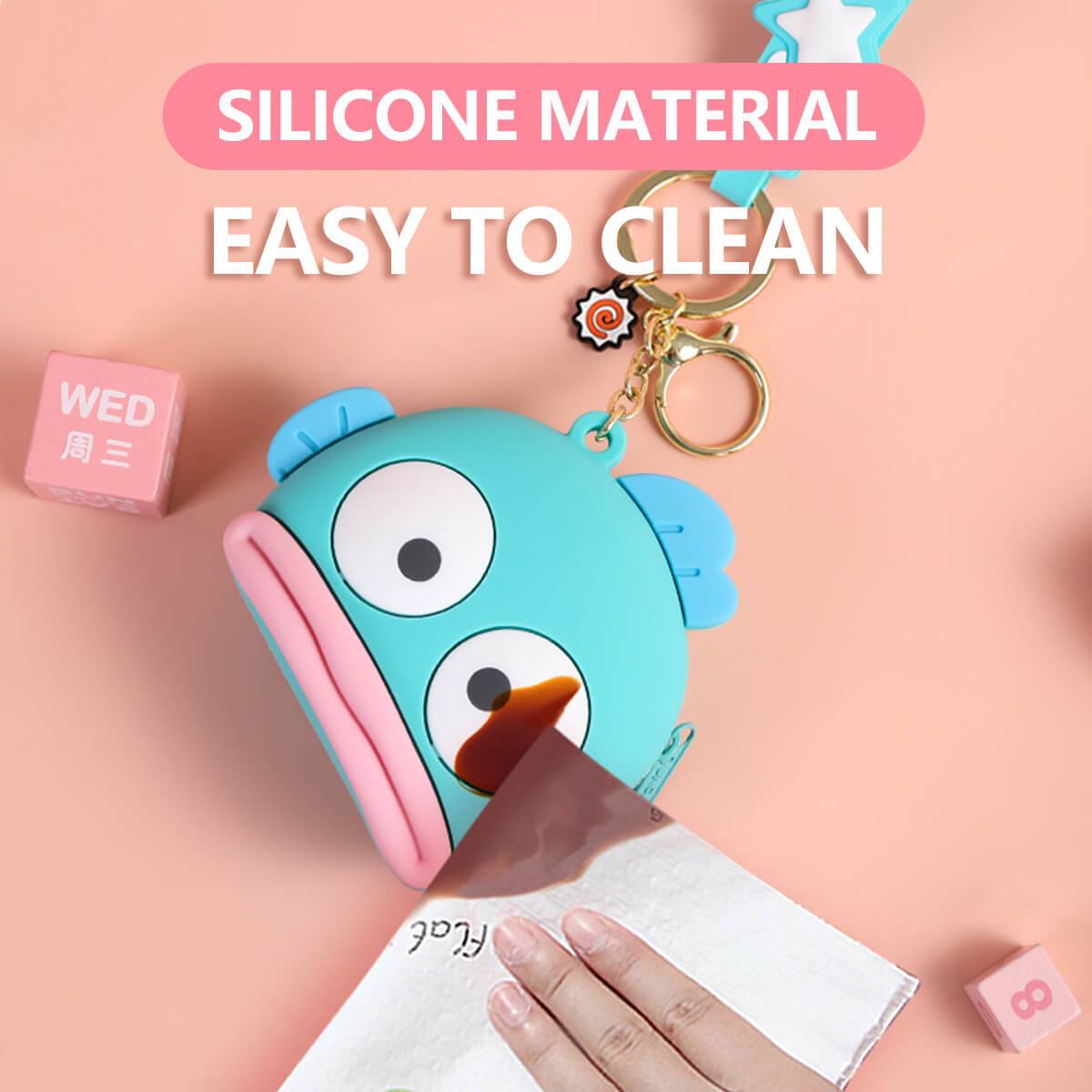 Close-up of blue fish-shaped Sanrio Cartoon Silicone Coin Purse Keychain being cleaned with a cloth. Made of easy-to-clean silicone material.