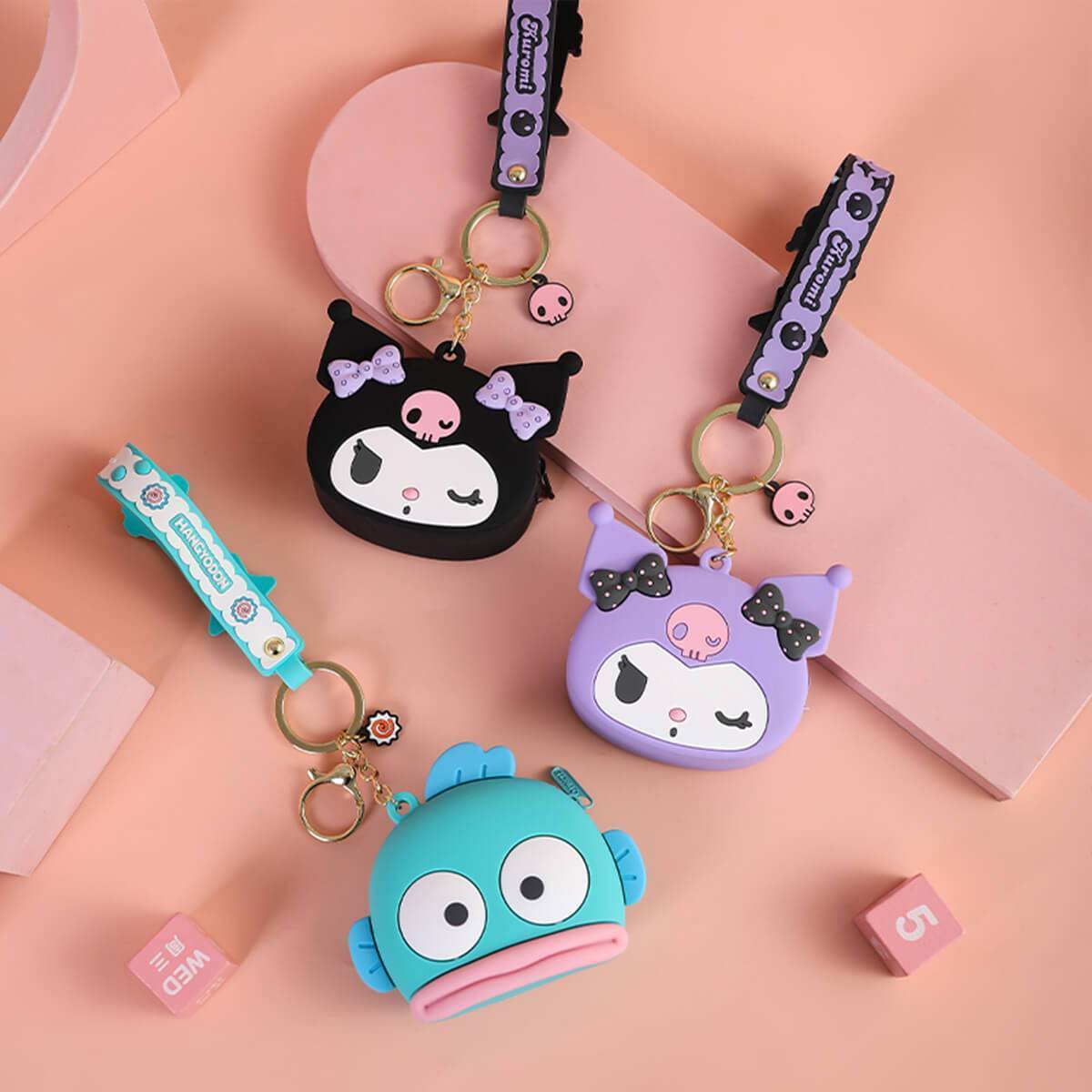 Three Sanrio Cartoon Silicone Coin Purse Keychains in black, purple, and blue displayed on a pastel background. Stylish and functional accessories.