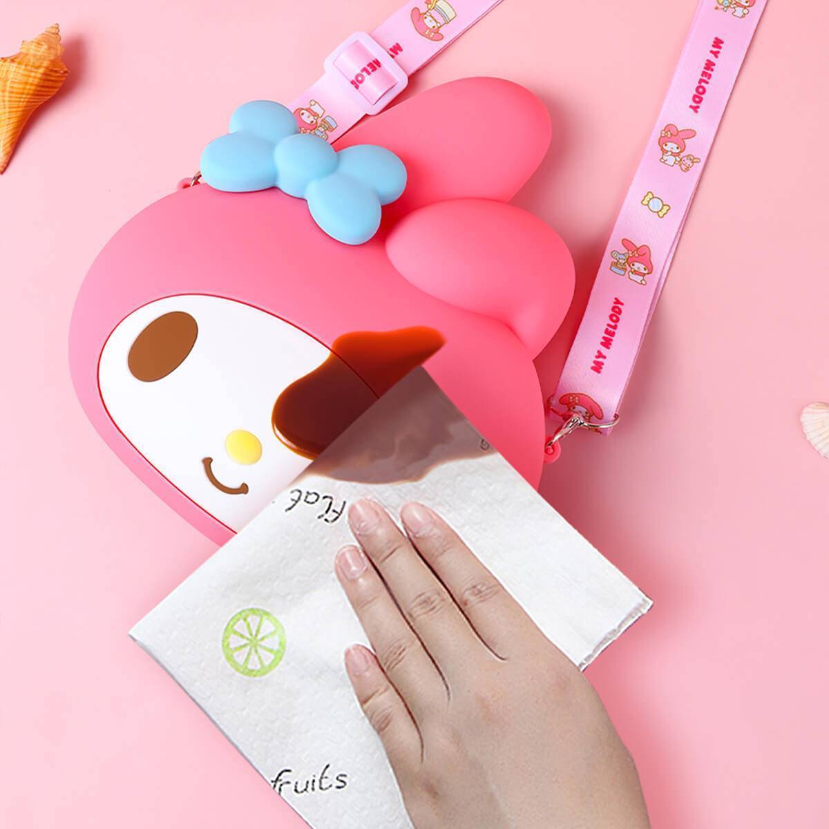 Waterproof pink Sanrio Cartoon Silicone Mini Crossbody Bag being wiped clean with a tissue, showcasing easy maintenance.
