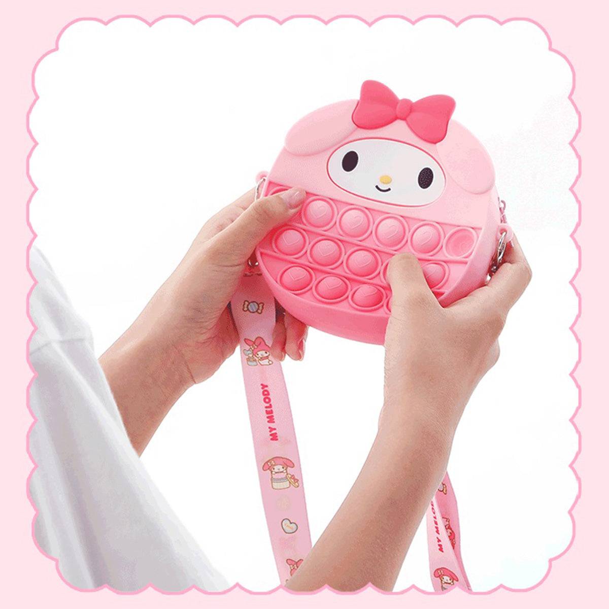 Hands pressing the pop bubbles on a My Melody-themed Sanrio Characters Pop It Bag. A fun and stress-relieving fidget toy with a cute design.