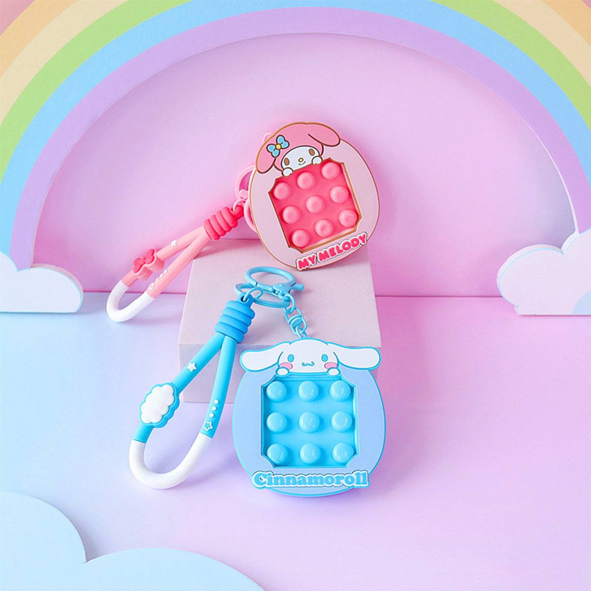 My Melody and Cinnamoroll Pop It Fidget Keychains on a pastel setup. Adorable Sanrio accessories designed for fidgeting and stress relief.
