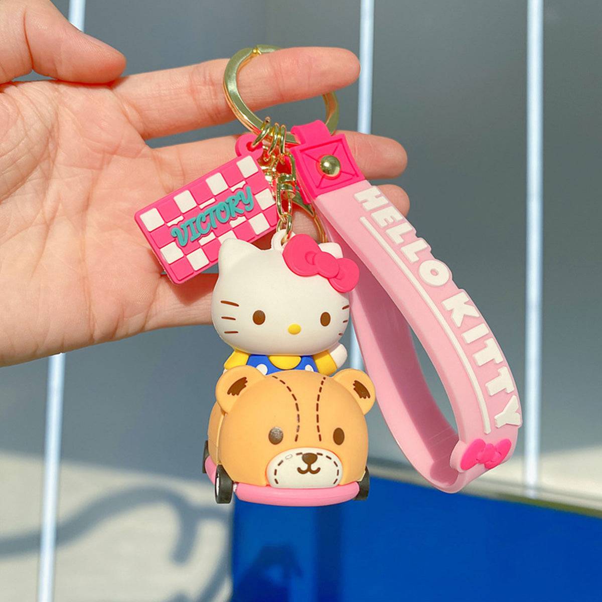 Sanrio on Race Car with Rolling Wheel Keychain featuring Hello Kitty in a bear-themed car with a pink wrist strap and 'VICTORY' charm.