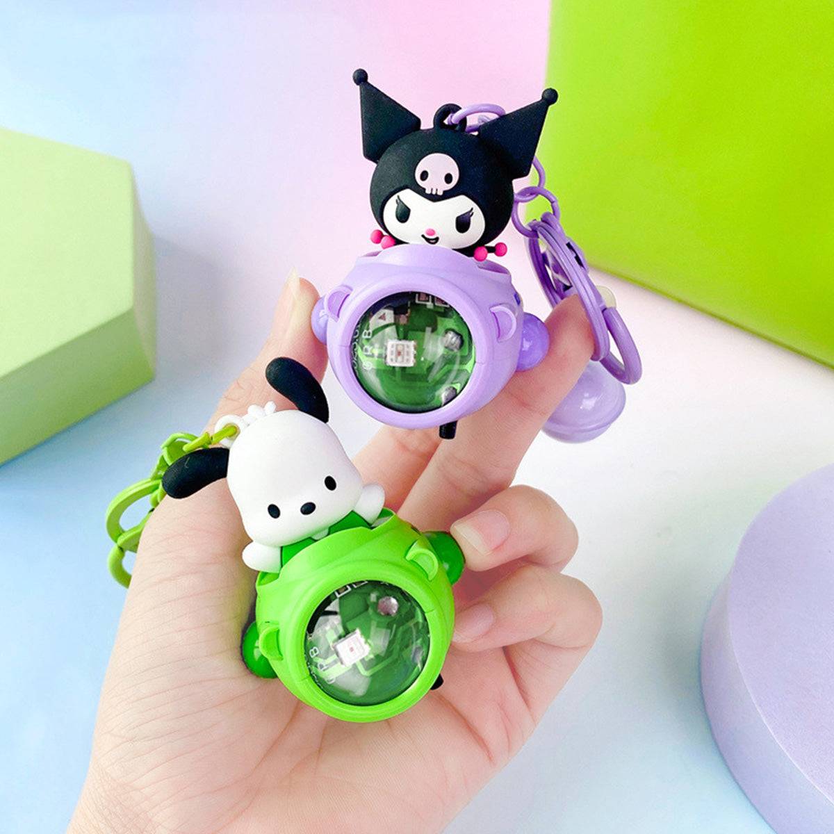 Hand holding Kuromi and Pochacco Sanrio Sunset Light Spaceship Keychains. A fun and collectible accessory with a glowing LED light.
