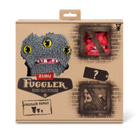 FUGGLER Soft Plush Toy in gray with three yellow eyes and red mystery figure in box. A collectible plush set for monster toy fans.