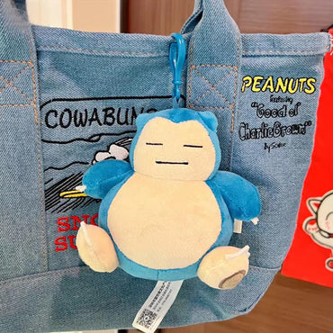 Adorable Pokemon Plush Snorlax Keychain 13.5cm attached to a denim bag, perfect for Pokémon fans to accessorize backpacks or purses.