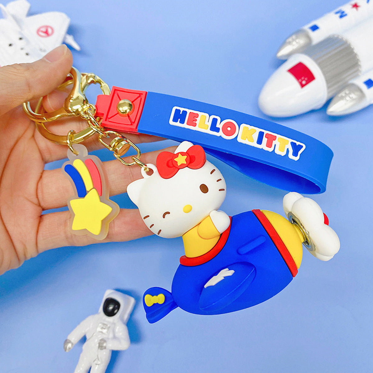 Sanrio Characters in Airplane Keychain featuring Hello Kitty in a blue and yellow airplane with a matching wrist strap. A cute collectible for fans.