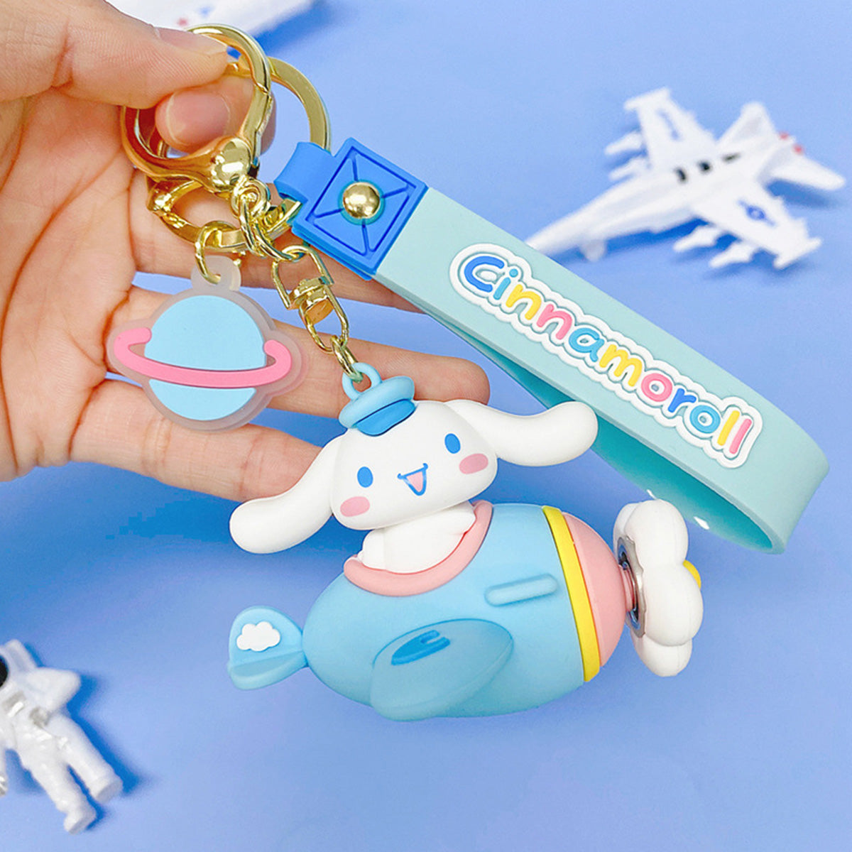 Sanrio Characters in Airplane Keychain featuring Cinnamoroll in a blue airplane with a matching wrist strap. A delightful collectible for fans.