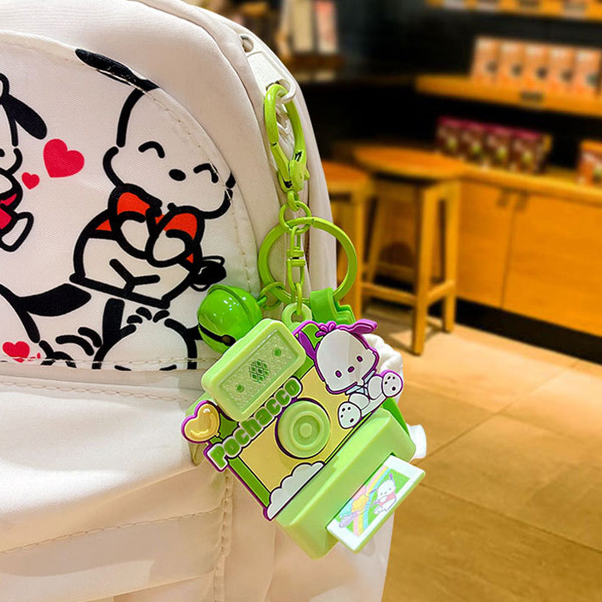 Pochacco Sanrio Characters Polaroid Camera Keychain clipped to a backpack, featuring a fun green design and functional camera details for collectors.