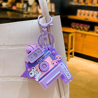 Kuromi Sanrio Characters Polaroid Camera Keychain hanging on a white handbag, highlighting its playful purple design and stylish charm for fans.