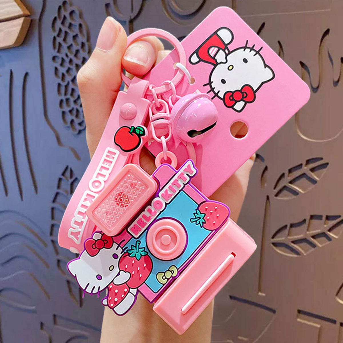 Hello Kitty-themed Sanrio Characters Polaroid Camera Keychain in pink with a strawberry design, bell charm, and wrist strap. A perfect gift for fans.