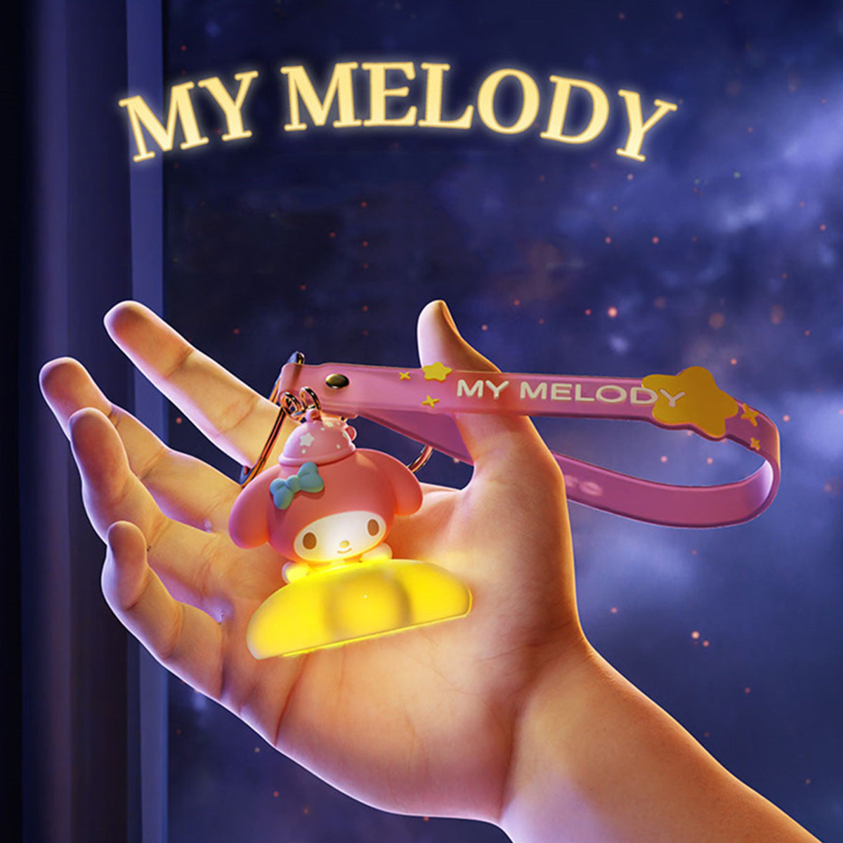 My Melody Sanrio Family Star Night Light Series Pendant Keychain with a glowing yellow base and pink strap, held in hand against a dreamy night scene.