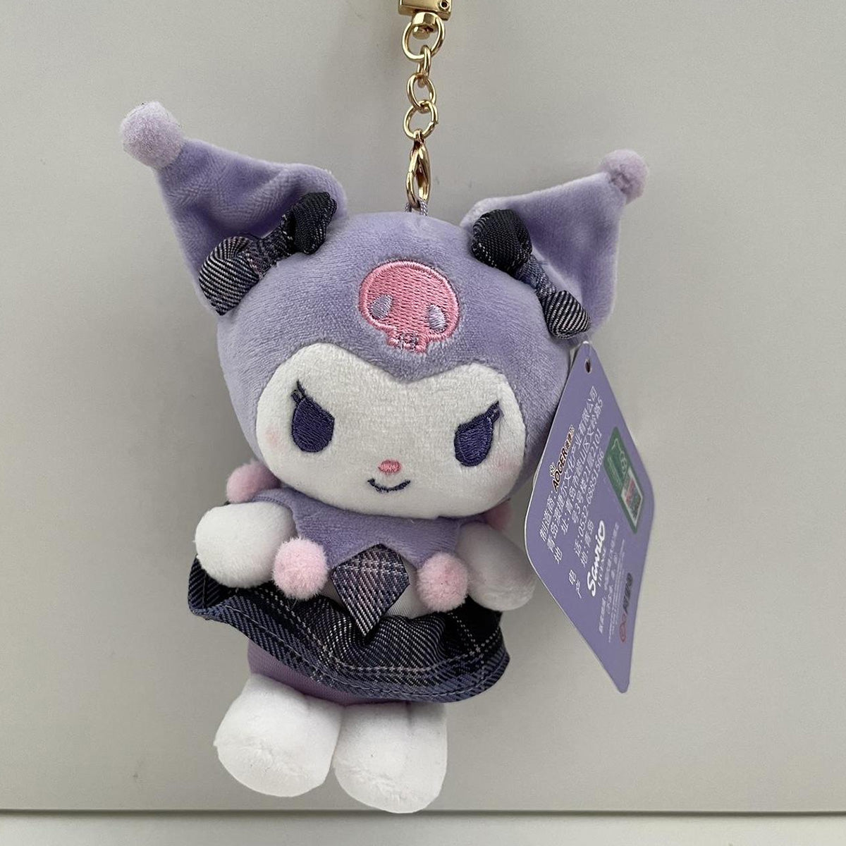 Sanrio JK Series Plush Keychain 10cm featuring Kuromi in a soft purple outfit with a plaid skirt and pom-pom details. Perfect for bags, keys, or as a collectible.