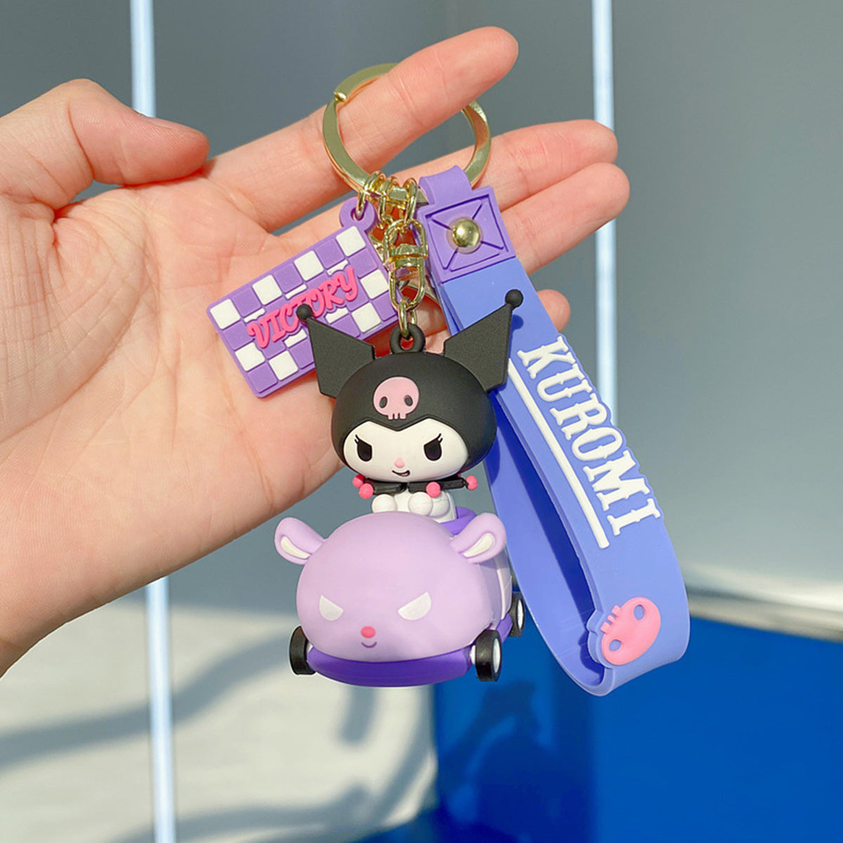 Sanrio on Race Car with Rolling Wheel Keychain featuring Kuromi in a purple car with a matching wrist strap and 'VICTORY' charm.